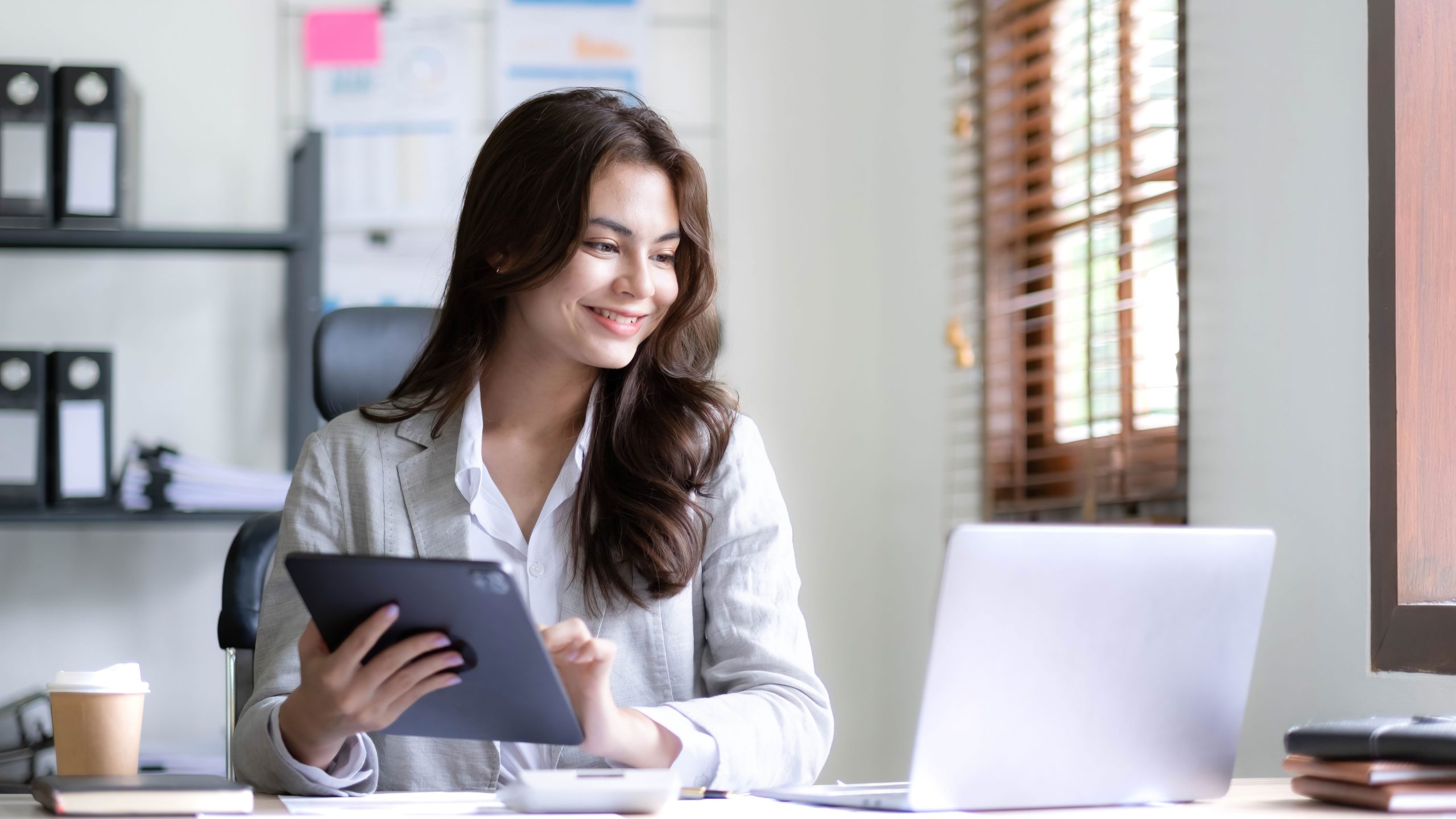 asian women carrying ipad and looking at laptop screen